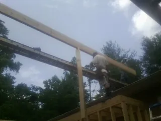 Carpenter setting a ridge beam over a new addition frame — Ice Dam Removal by Roofing Brothers in Horatio