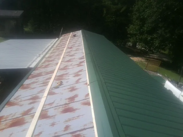Old rusted panels beside newly installed green metal roofing — Wind Damage Roof Repair by Roofing Brothers in Horatio