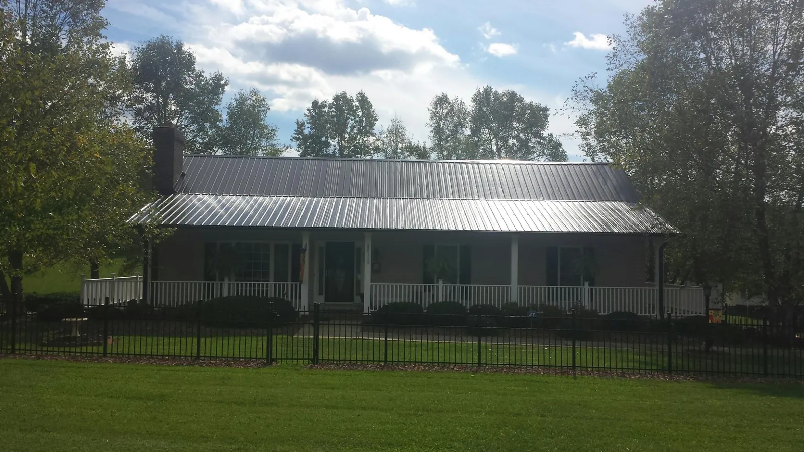 Gray metal roof on a brick ranch with a full width front porch — Gutter Guard Installation work by our crew in Horatio