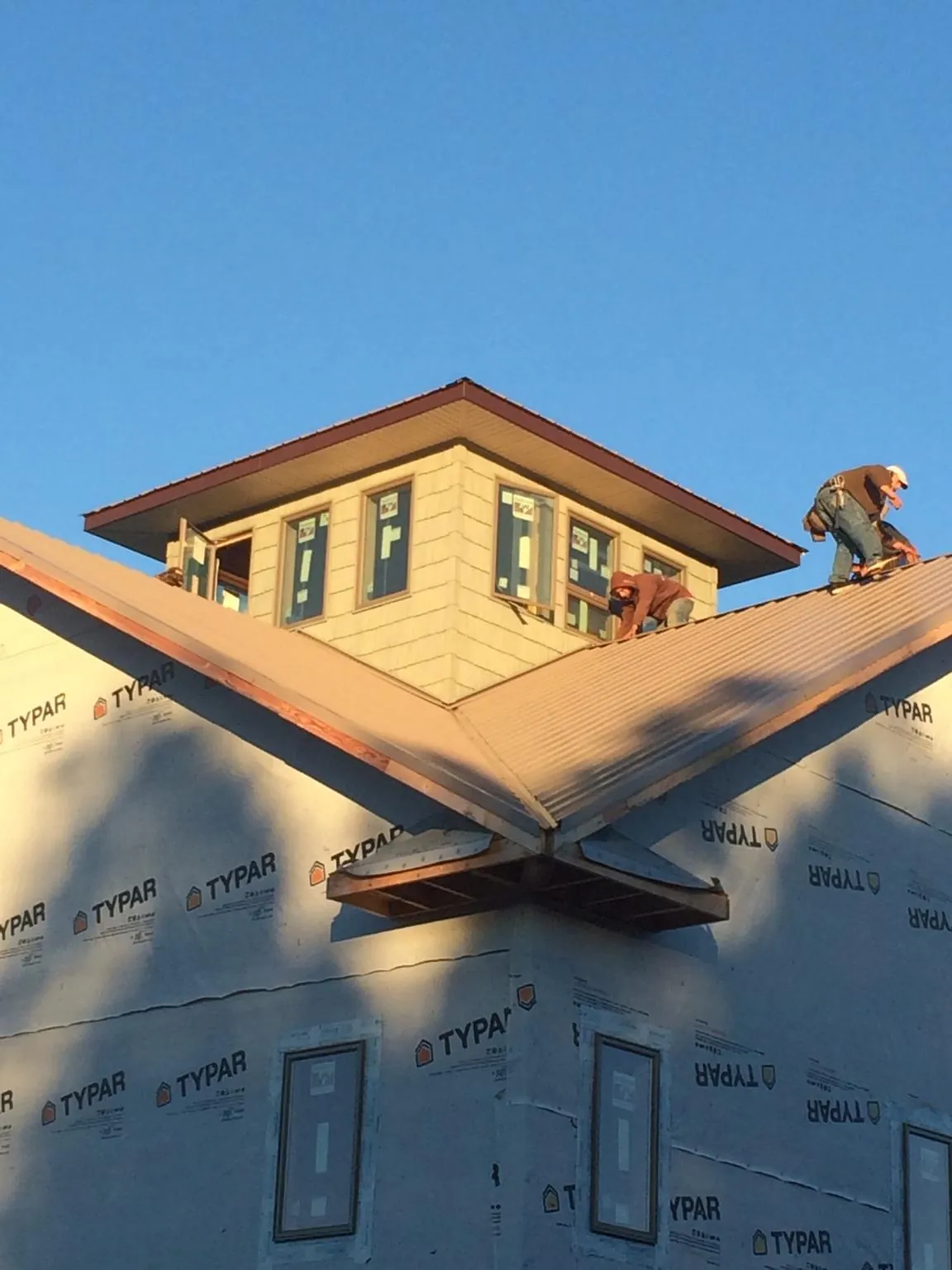 Roofers working around a rooftop cupola on a new metal roof at sunset — Roof Waterproofing in Horatio by Roofing Brothers